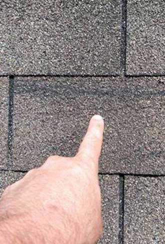 Damaged shingles identified during a roof inspection highlighting the need for repair