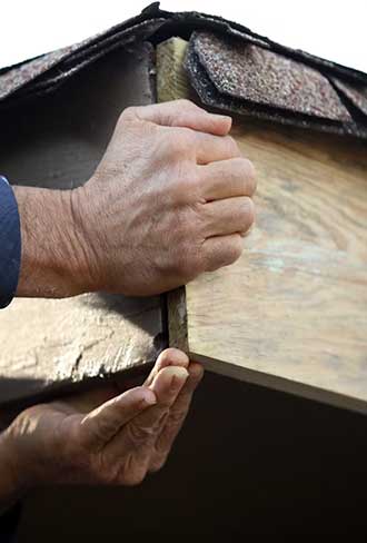 Roof inspector checking shingles for damage and wear during routine roof inspection